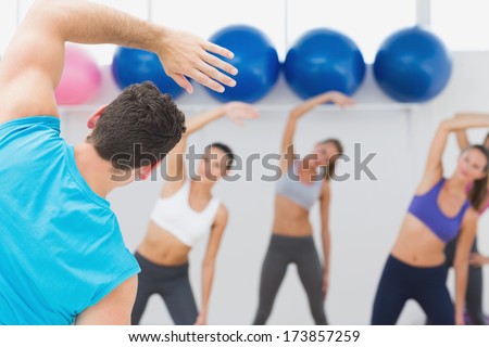 Instructor and fitness class doing stretching exercise in fitness studio