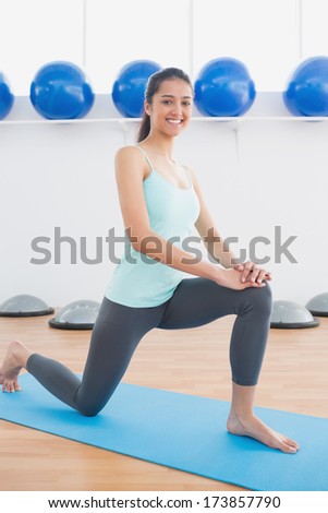 Portrait of a sporty young woman stretching leg in fitness studio