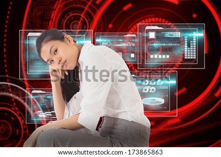 Businesswoman sitting cross legged leaning on hand against shiny red circles on black background