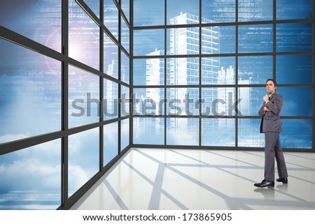 Thoughtful businessman holding pen to chin against cityscape seen through window