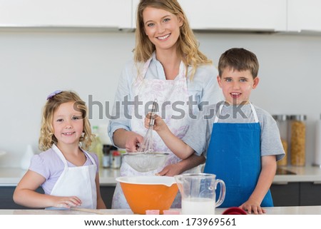 Portrait of mother with son and daughter baking cookies at counter top in kitchen