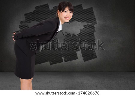 Smiling businesswoman bending against display on wall showing global technology graphic