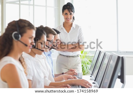 Portrait of happy female manager with business staff working in a call center