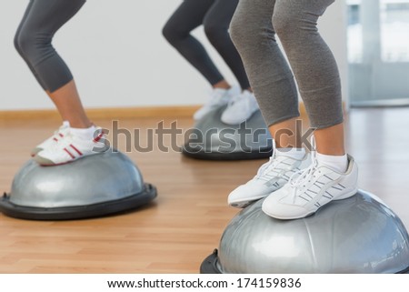 Closeup low section of fit people performing step aerobics exercise in gym