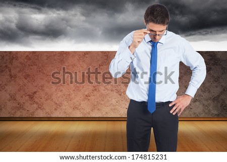 Thinking businessman tilting glasses against dark sky beyond balcony