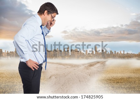Thinking businessman tilting glasses against path in yellow field leading to city