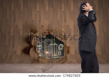 Stressed businessman with hands on head against rip on wall showing technology interface