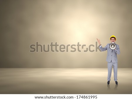 Architect with hard hat shouting with a megaphone against grey room
