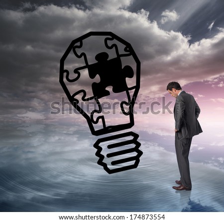 Businessman with hands on hips against light bulb graphic on colourful horizon