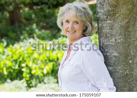 Side view portrait of a mature woman leaning against tree trunk in the park