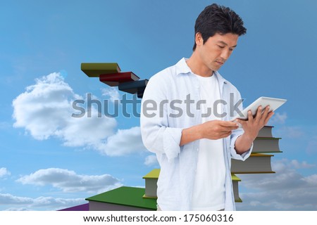 Male looking at his tablet computer against book steps against sky