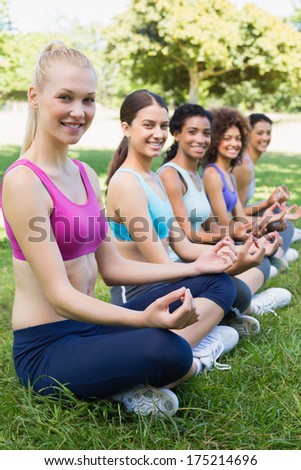 Portrait of happy female friends performing yoga exercise at park