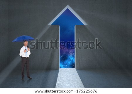 Happy businessman holding umbrella against arrow door in dark room
