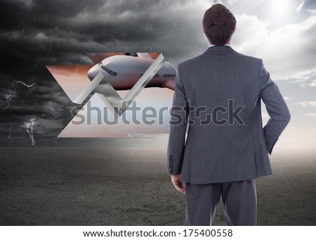 Businessman standing with hand on hip against ominous landscape