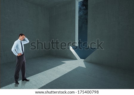 Thoughtful businessman with hand on head against arrow door in dark room
