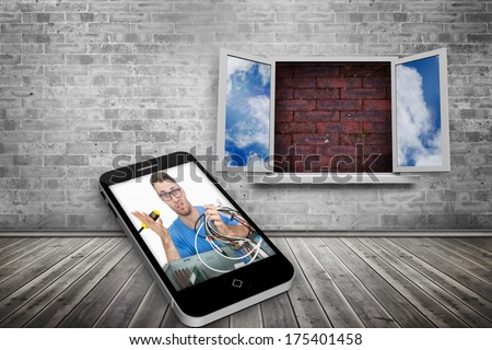It technician on smartphone screen against window frame on red brick wall