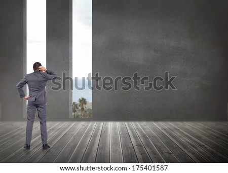 Thinking businessman scratching head against grey room with windows showing the ocean