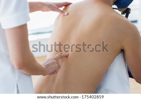 Midsection of male patient receiving back massage by female therapist in hospital