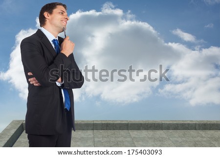 Thinking businessman holding pen against balcony and cloudy sky
