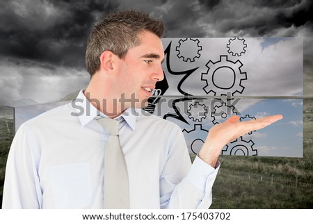 Smiling businessman looking at hand against stormy countryside background