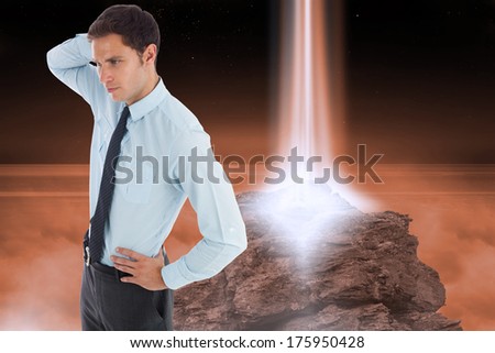 Thinking businessman scratching head against rocky landscape with light beam
