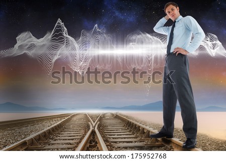 Thinking businessman with hand on head against train tracks under energy wave in desert