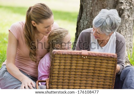 Grandmother mother and daughter with picnic basket sitting at the park