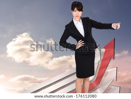 Businesswoman pointing against red and grey curved arrows pointing against sky
