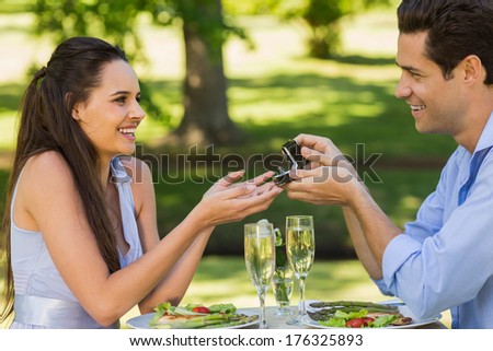 Side view of a man proposing woman while they have a romantic date at an outdoor cafÃ?Â©