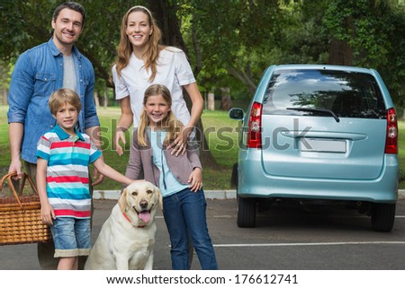 Portrait of a happy family of four with car at picnic