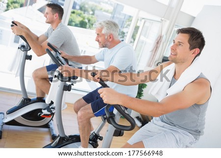 Three men exercising on fitness bikes at gym