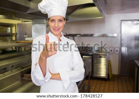Portrait of a smiling female cook gesturing thumbs up in the kitchen