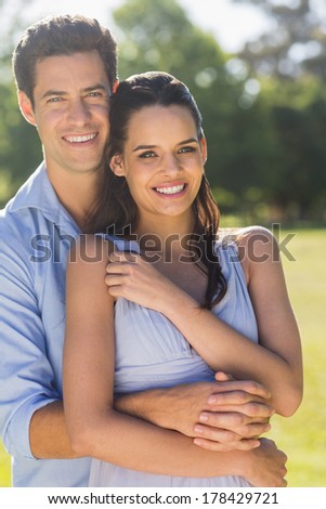 Portrait of a smiling man embracing woman from behind at the park