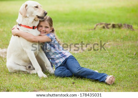 Full length portrait of a young girl hugging pet dog at the park