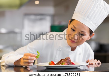 Closeup of a concentrated female chef garnishing food in the kitchen