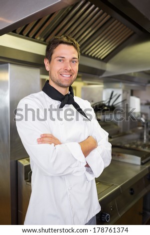 Portrait of a smiling male cook with arms crossed standing in the kitchen