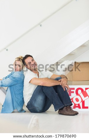 Side view portrait of a smiling couple with boxes in a new house