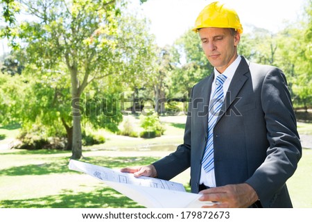 Well dressed businessman studying blueprint in park