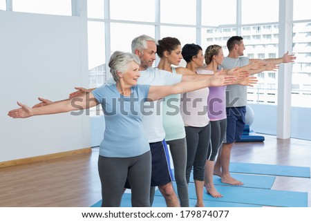 Portrait of fitness class stretching hands in row at yoga class