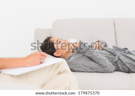 Therapist taking notes on her crying patient on the couch at therapy session