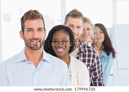Design team standing in a line smiling at camera in creative office