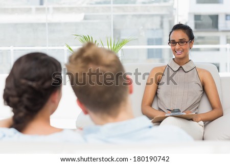 Therapist smiling at couple on the couch in therapists office