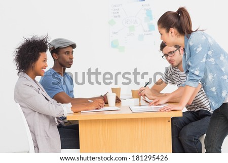 Side view of a group of artists in discussion at desk at the office