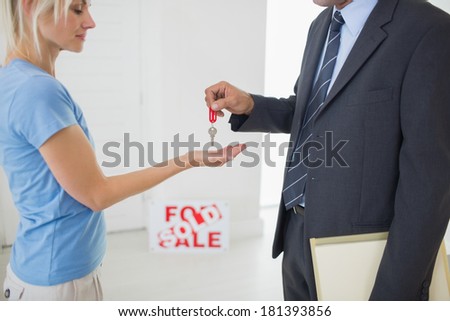 Side view mid section of a real estate agent passing house key to woman