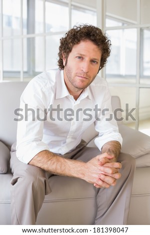 Portrait of a well dressed relaxed young man sitting on sofa in the house
