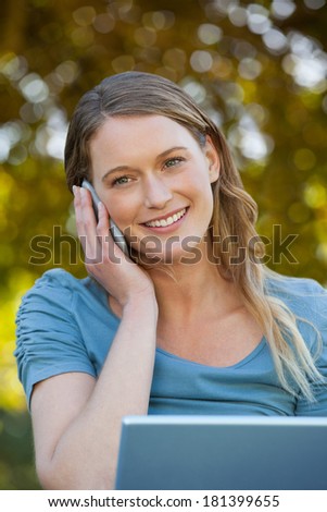 Close-up of a relaxed young woman using laptop and mobile phone at the park