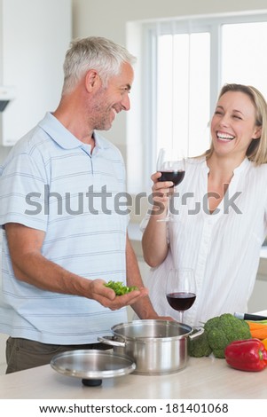 Laughing couple making dinner together at home in the kitchen
