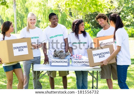 Group of male and female volunteers with donation boxes in park