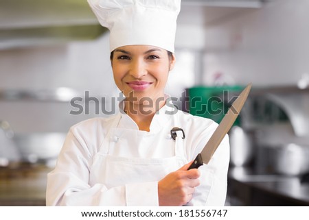 Portrait of a confident female cook holding knife in the kitchen