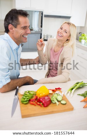 Cheerful couple with chopped vegetables in the kitchen at home